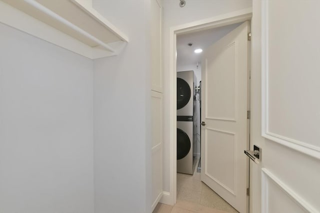 laundry room with stacked washer and dryer and light tile patterned flooring