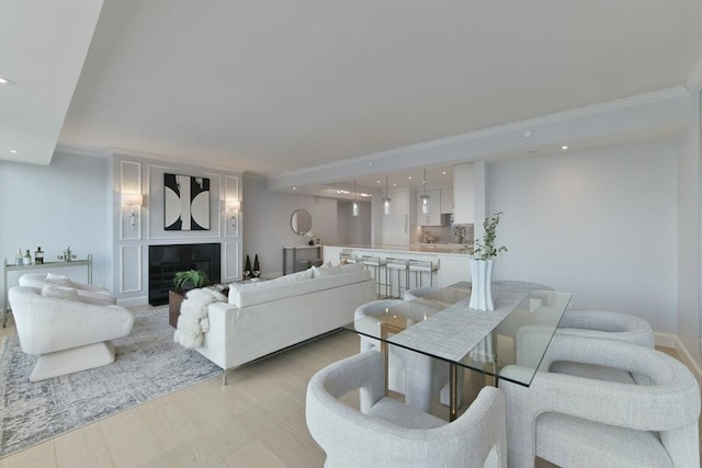 living room featuring ornamental molding, a large fireplace, and light hardwood / wood-style flooring