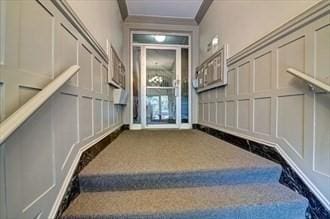 stairway featuring a decorative wall, ornamental molding, and carpet floors
