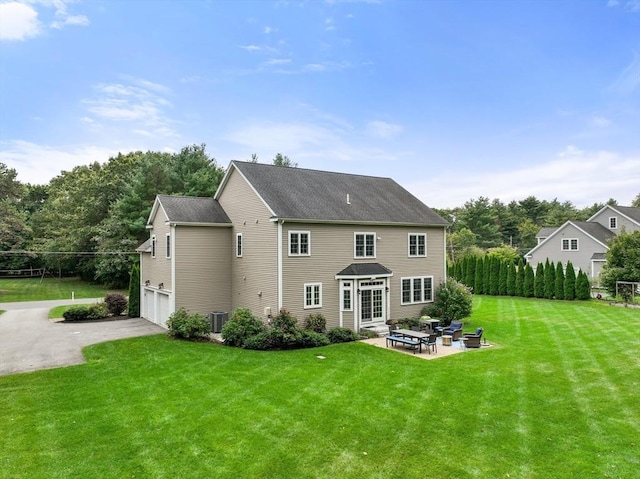 rear view of property featuring a garage, a yard, a patio area, and driveway