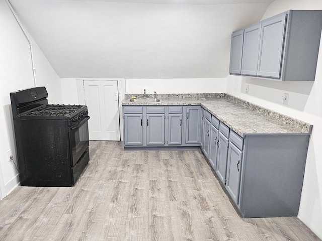21 High St, South Hadley, MA 01075 - kitchen with black gas range oven, light wood-type flooring, vaulted ceiling, gray cabinets, and light stone countertops