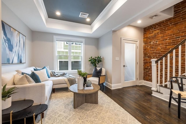 living room with wood-type flooring, crown molding, and a tray ceiling