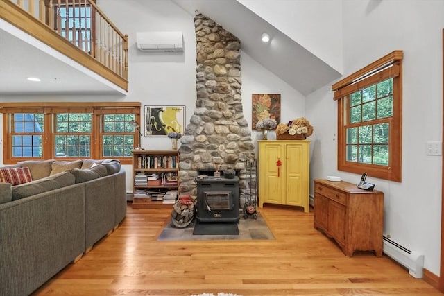 236 Ridge Ave, Otis, MA 01253 - living area with a baseboard radiator, a wood stove, high vaulted ceiling, an AC wall unit, and wood finished floors
