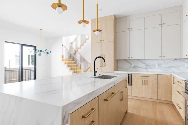 1597 Centre St Unit A, Newton, MA 02461 - kitchen with light brown cabinets, light stone countertops, an island with sink, light wood-style flooring, and tasteful backsplash