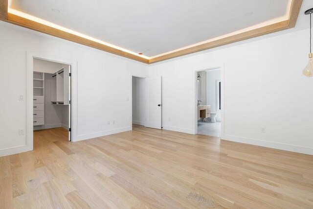1597 Centre St Unit A, Newton, MA 02461 - unfurnished bedroom with light wood-style floors, a spacious closet, a tray ceiling, and ensuite bath
