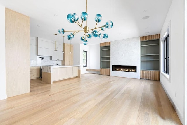 1597 Centre St Unit A, Newton, MA 02461 - unfurnished living room featuring built in shelves, light wood-type flooring, a fireplace, and a chandelier
