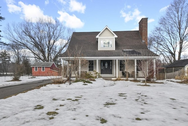 view of front of house featuring an outbuilding, covered porch, and a chimney