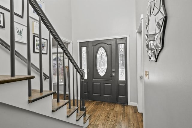 entryway featuring stairway, wood finished floors, baseboards, and a towering ceiling