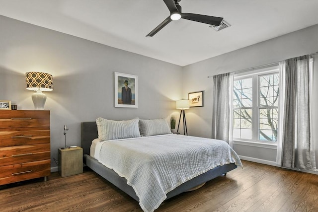 bedroom featuring ceiling fan, wood finished floors, visible vents, and baseboards