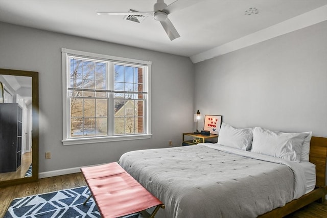 bedroom featuring visible vents, ceiling fan, baseboards, and wood finished floors