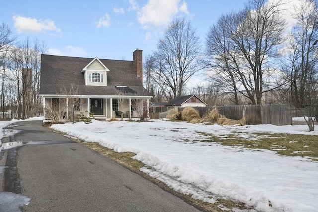 cape cod-style house featuring a chimney and fence