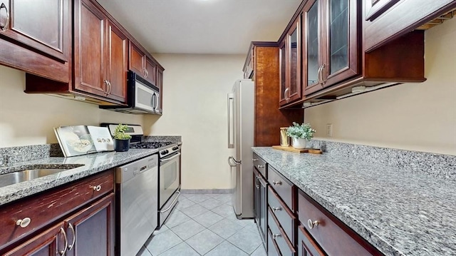 99 Pond Ave Unit 326, Brookline, MA 02445 - kitchen featuring stainless steel appliances, light tile patterned flooring, light stone countertops, glass insert cabinets, and baseboards