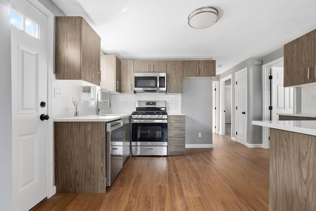 kitchen with tasteful backsplash, sink, stainless steel appliances, and dark hardwood / wood-style floors