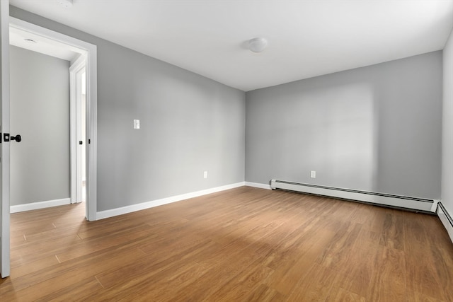 spare room with baseboard heating and light wood-type flooring