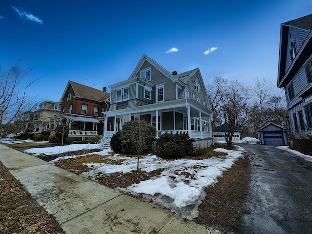 view of front facade featuring a garage, covered porch, driveway, and an outdoor structure