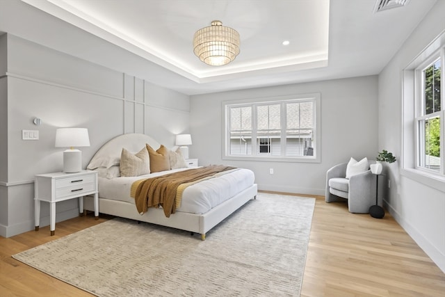 bedroom with a tray ceiling and hardwood / wood-style flooring