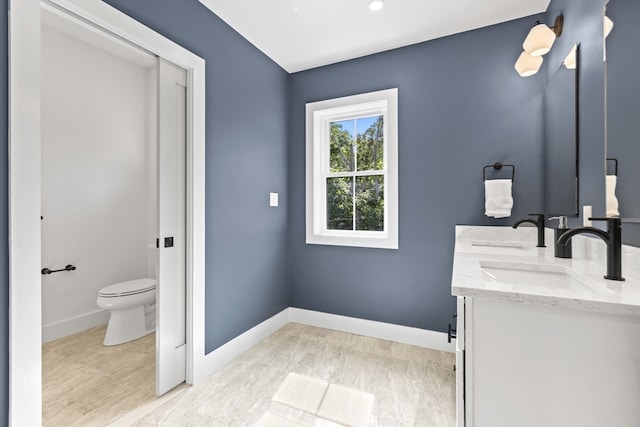 bathroom with toilet, vanity, and wood-type flooring