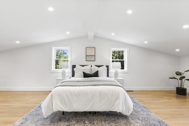 bedroom featuring multiple windows, light wood-type flooring, and vaulted ceiling with beams