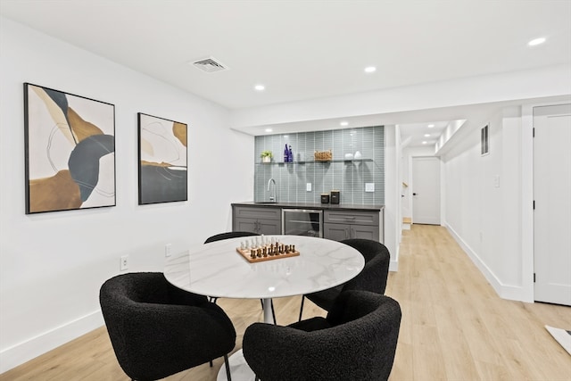 dining area featuring wine cooler, indoor bar, and light hardwood / wood-style flooring