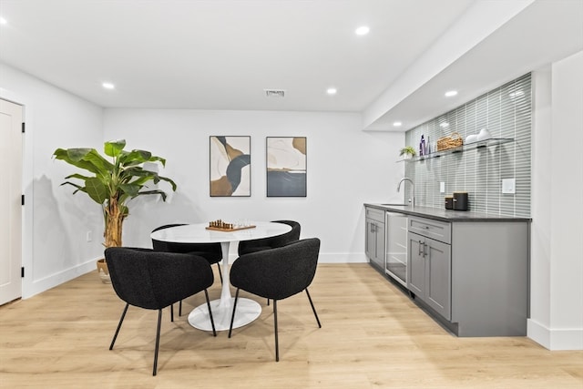 dining area with beverage cooler, light wood-type flooring, and wet bar