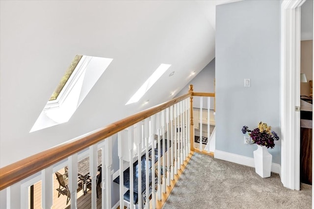 corridor featuring carpet floors and vaulted ceiling with skylight