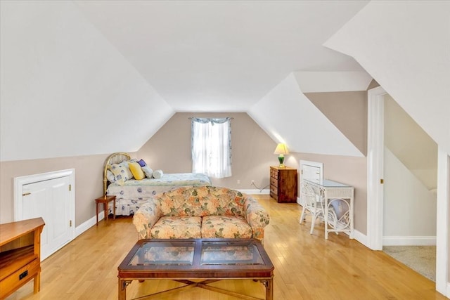 bedroom with baseboards, lofted ceiling, and wood finished floors