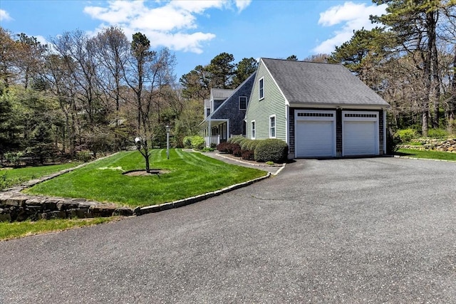 view of property exterior featuring a garage, a shingled roof, a yard, and aphalt driveway