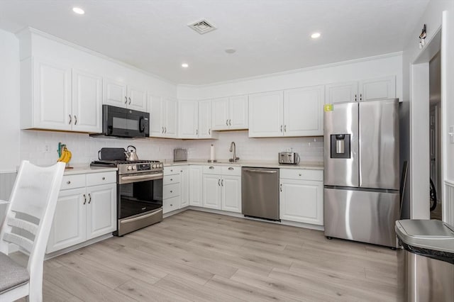 62 Maple St Unit J, Canton, MA 02021 - kitchen featuring appliances with stainless steel finishes, white cabinets, light wood-style flooring, and recessed lighting