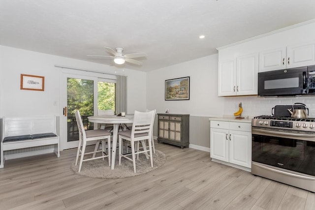 62 Maple St Unit J, Canton, MA 02021 - kitchen with black microwave, gas range, light wood-style flooring, white cabinets, and wainscoting