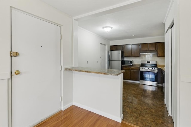 21 Central Ave Unit 30, Everett, MA 02149 - kitchen featuring appliances with stainless steel finishes, dark brown cabinets, under cabinet range hood, tasteful backsplash, and a peninsula