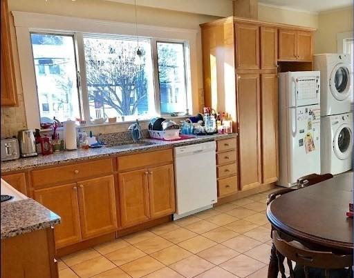 562 Main, Medford, MA 02155 - kitchen featuring white appliances, stacked washing machine and dryer, a sink, light stone countertops, and light tile patterned floors