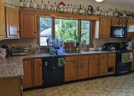 562 Main, Medford, MA 02155 - kitchen featuring black appliances, a sink, light countertops, brown cabinetry, and light flooring