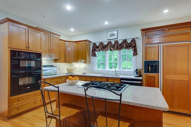 43 Old Concord Rd, Lincoln, MA 01773 - kitchen with stovetop with downdraft, light wood-type flooring, a sink, a breakfast bar area, and tasteful backsplash