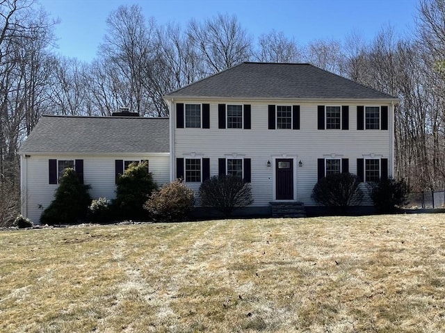 colonial home with a chimney and a front lawn