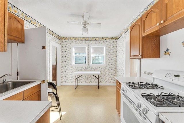 kitchen featuring ceiling fan, white range with gas cooktop, and sink