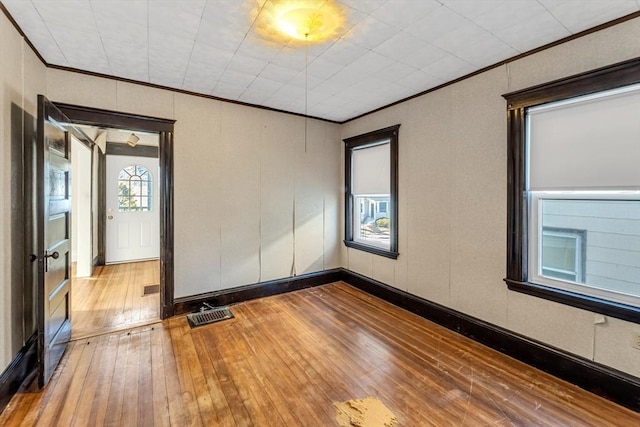 empty room with ornamental molding and hardwood / wood-style floors