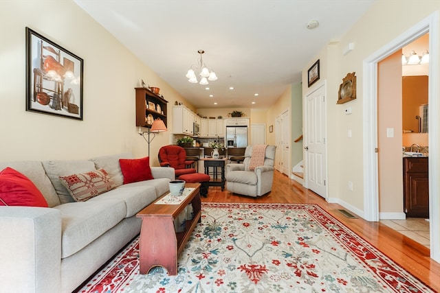 living room with light hardwood / wood-style flooring, sink, and a chandelier