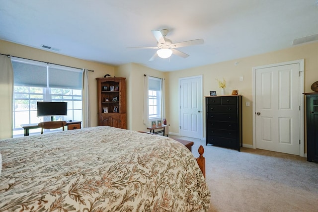 bedroom with light colored carpet, ceiling fan, and multiple windows