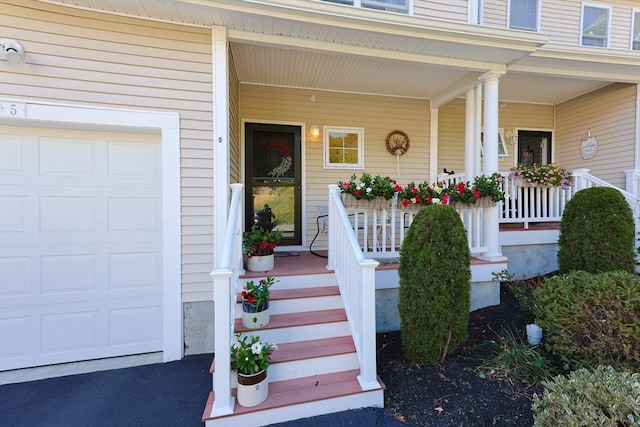 view of exterior entry featuring a garage and a porch