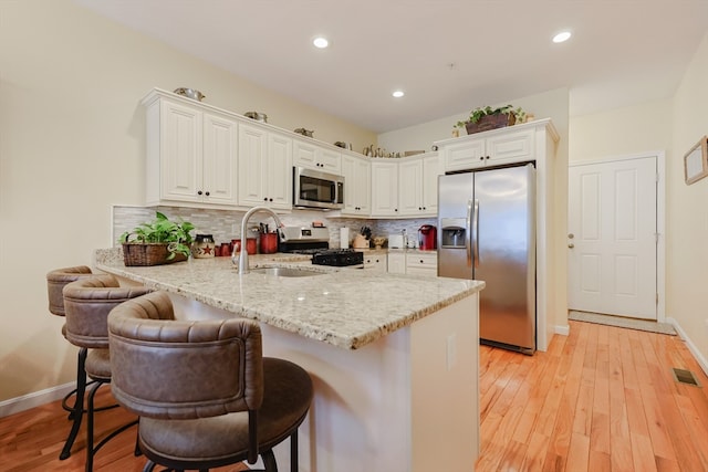 kitchen with stainless steel appliances, a kitchen breakfast bar, kitchen peninsula, and white cabinets