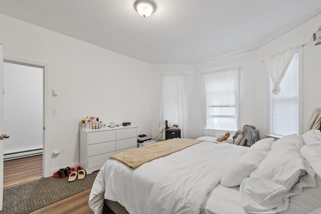 bedroom with baseboard heating and wood-type flooring