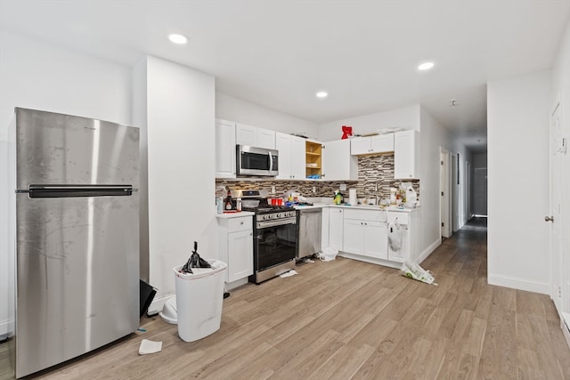 kitchen featuring light wood-type flooring, white cabinets, appliances with stainless steel finishes, and tasteful backsplash