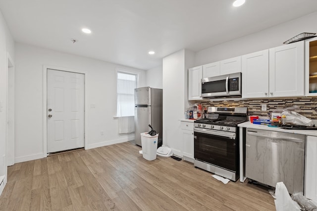 kitchen with light hardwood / wood-style flooring, stainless steel appliances, backsplash, and white cabinets