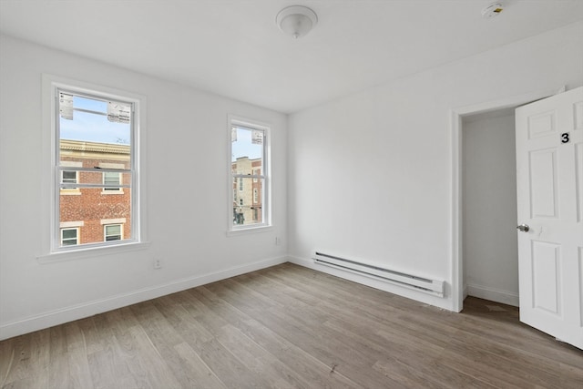 interior space featuring a baseboard heating unit, plenty of natural light, and wood-type flooring