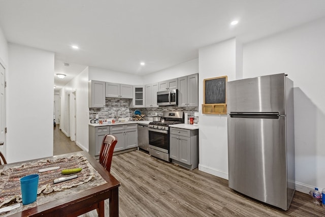 kitchen with tasteful backsplash, gray cabinetry, appliances with stainless steel finishes, and light hardwood / wood-style floors