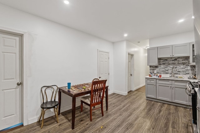 kitchen with backsplash, stainless steel range oven, sink, gray cabinets, and dark hardwood / wood-style floors