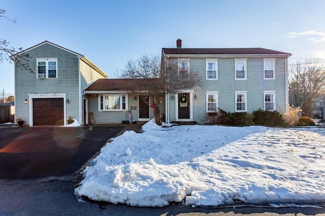 view of front of home featuring aphalt driveway, a chimney, and a garage