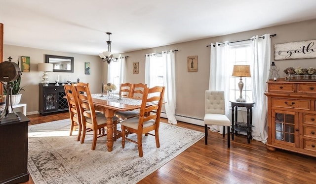 dining area with a notable chandelier, dark wood finished floors, and baseboard heating