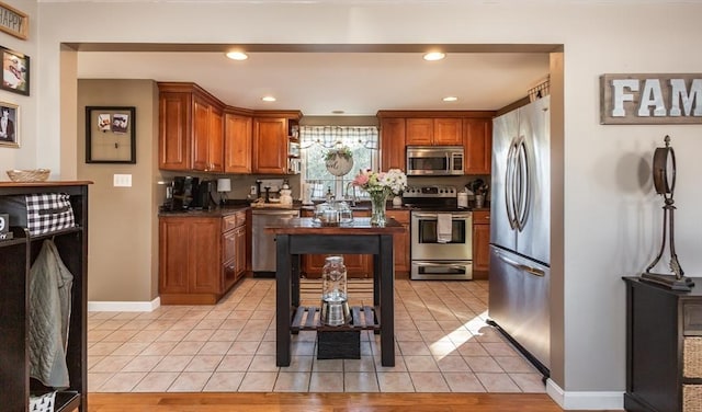 kitchen featuring light tile patterned floors, recessed lighting, stainless steel appliances, baseboards, and brown cabinets