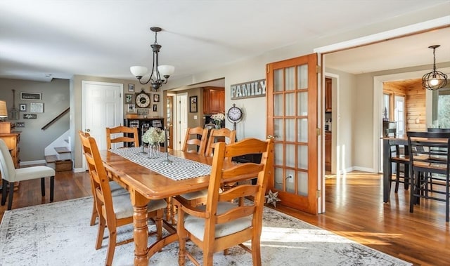 dining area with light wood-style floors, baseboards, stairs, and a chandelier